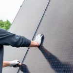 Komplettsysteme zur Strom- und Wärmeerzeugung: Nahaufnahme eines Monteurs in Handschuhen, der ein Solarmodul installiert.