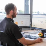 Photovoltaik-Fernüberwachung: Ein Techniker sitzt vor zwei Bildschirmen und überwacht die Leistung von Solaranlagen.