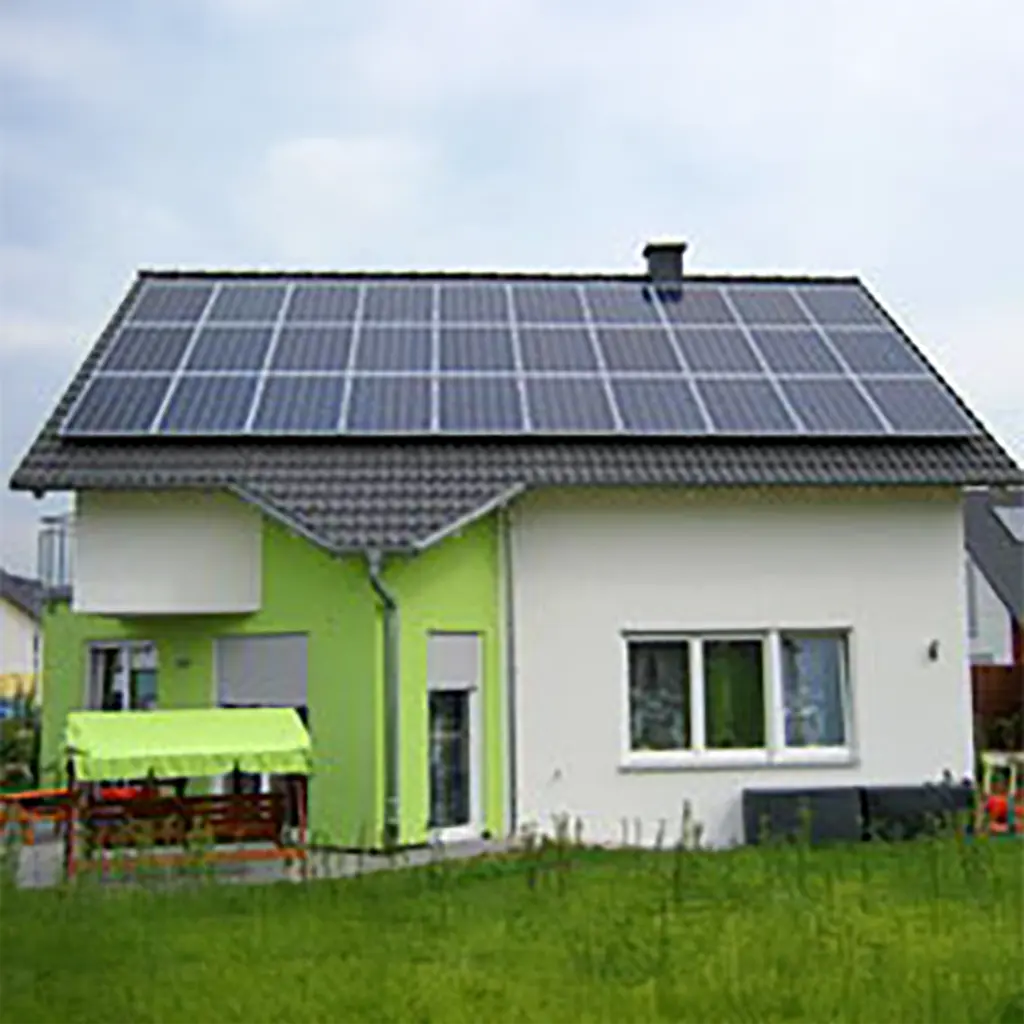 Photovoltaik Bad Friedrichshall: Große Solaranlage auf Hausdach mit weiß-grüner Fassade.