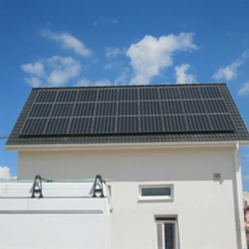 Photovoltaik Bretzfeld: Dunkle Solarmodule auf Hausdach bei Sonnenschein, weißes Fahrzeug im Vordergrund.