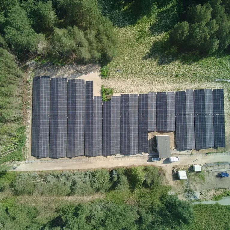 Freilandanlage Rückersdorf: Senkrechte Luftaufnahme der PV-Anlage umgeben von Wald und Bäumen.
