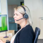 Mitarbeiterin im Kundenservice mit Headset am Schreibtisch; bereit für Widmann Kontakt und Support.